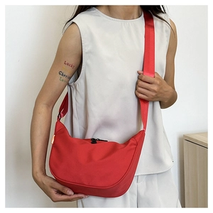 Detail of red crescent shoulder bag featuring nylon material and adjustable strap