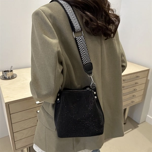 Sac seau noir avec strass et bandoulière à chevrons porté par un mannequin en intérieur