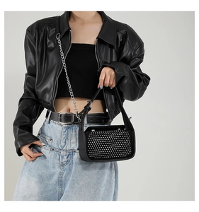 Detail of punk style black leather bag with silver rivets and metal chain shoulder strap