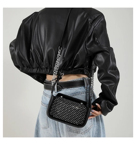 Detail of black mini crossbody bag with silver stud accents and metal chain strap