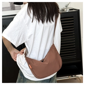 Detail of a brown crescent crossbody bag with durable nylon fabric and orange brand label