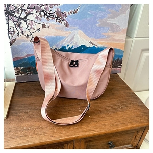Detail of pink waterproof nylon dumpling bag with adjustable strap on wooden surface