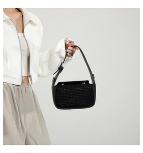 Detail of black rhinestone shoulder bag with adjustable strap on a female model