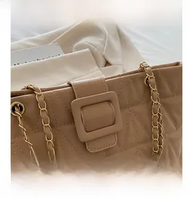 Dettaglio borsa a tracolla trapuntata beige con fibbia in metallo e tracolla a catena