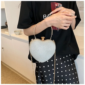 Detail of a sparkling heart-shaped evening bag with silver sequins and a gold metal handle
