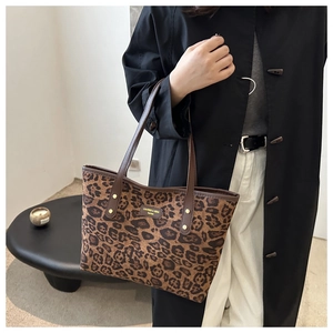 Détail du sac cabas léopard avec poignées en cuir marron et rivets en métal doré