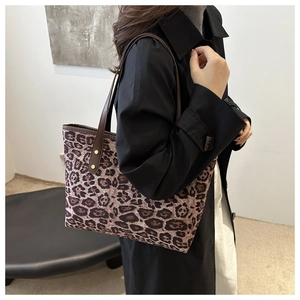 Leopard print tote bag with brown leather straps and gold studs shown on a model
