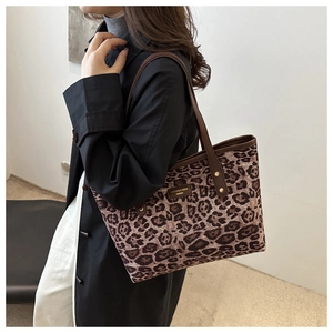 Gros plan du sac cabas léopard avec anses en cuir marron et détails du logo de marque
