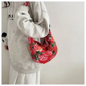 Détail du sac hobo rouge avec motif floral de pivoines et bandoulière large confortable