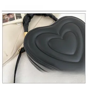 Detail of heart-shaped black handbag featuring quilted layers and ruched handle