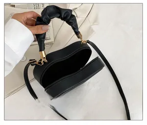Detail of black heart-shaped handbag showing internal compartment and zip closure
