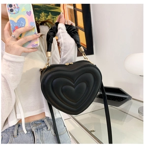 Detail shot of heart-shaped embossed pattern and ruffled handle on black PU leather bag