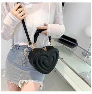 Detail of heart-shaped crossbody bag with quilted PU leather and gold metal hardware