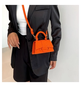 Close-up of orange mini square handbag with geometric texture and metallic buckle