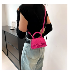 Detail of fuchsia mini square bag with geometric texture and golden hardware