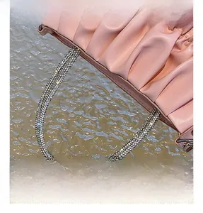 Detail shot of the pink pleated handbag featuring a luxurious crystal-encrusted handle