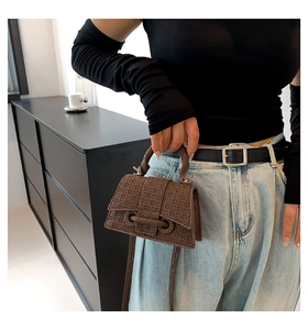 Detailed macro view of brown woven texture handbag with sleek handle and strap