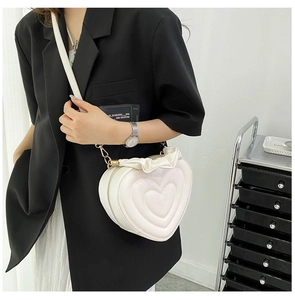 Detail of white heart-shaped crossbody bag with ruffled edges and embossed texture