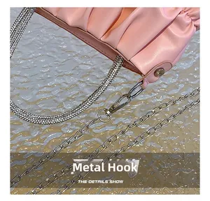 Detail view of pink pleated handbag showing silver metal hooks and rhinestone shoulder strap
