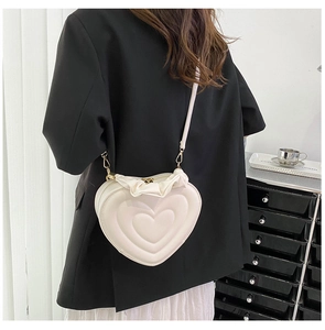 Back view of a model wearing a cream heart-shaped crossbody bag with ruffled edges
