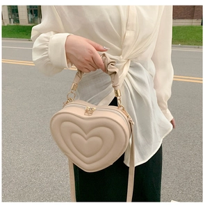 Detail of beige heart-shaped bag showing 3D embossed texture and ruffled handle