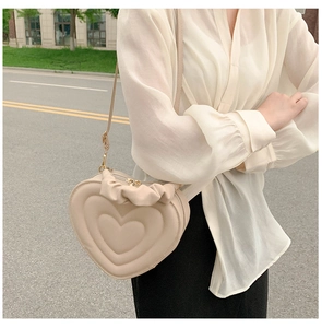 Chic cream heart-shaped crossbody bag with ruffle trim and thin shoulder strap