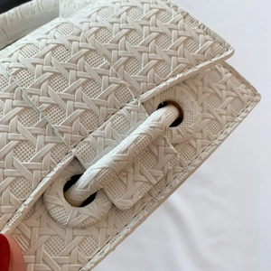 Detail of premium woven white leather bag featuring a cylindrical closure and minimalist design