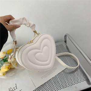 Detail of white heart-shaped PU leather bag with embossed texture and gold zipper hardware