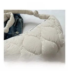 Detailed close-up of white quilted nylon dumpling bag with wave stitching and knot strap