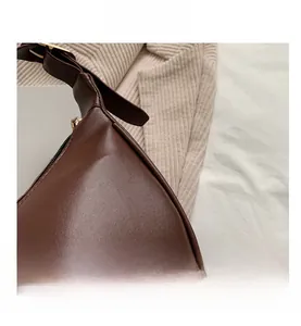 Detail view of smooth brown hobo bag with gold adjustable buckle and leather texture