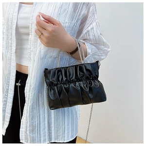 Close-up of black pleated leather handbag with sparkling rhinestone encrusted handles
