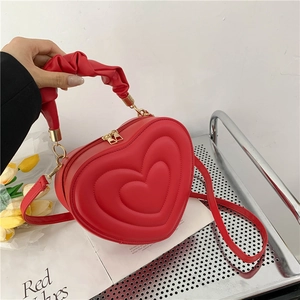 Detail of red heart-shaped handbag with quilted pattern and gathered cloud handle