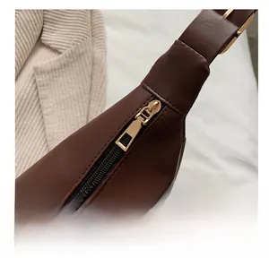 Detail of smooth gold zipper and stitching on brown leather crossbody saddle bag