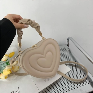 Detail of beige heart-shaped bag with ruched cloud handle and multi-layer embossed texture