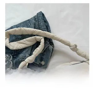 Detailed close-up of a beige quilted handbag featuring a creative knotted handle design