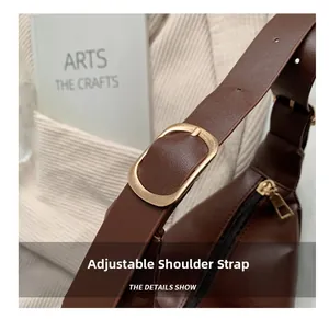 Detail of deep brown leather saddle bag with adjustable strap and golden metal buckle