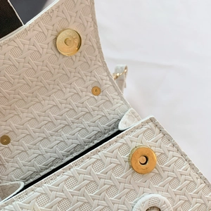 Detail view of woven white handbag with magnetic gold closures and dark interior lining