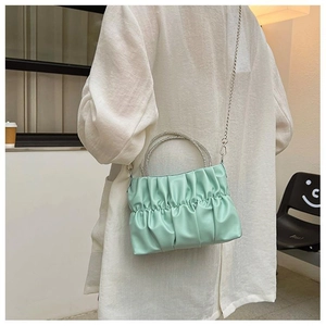 Green ruched cloud bag with rhinestone circular handles shown on a model's back