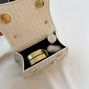 Macro view of white woven shoulder bag interior showing capacity for cosmetics and earbuds