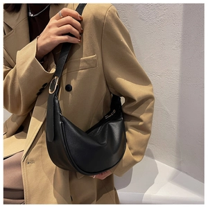 Detail of black semi-circle hobo bag with gold buckle and wide shoulder strap
