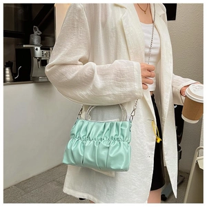 Close-up of mint green pleated leather bag with a sparkling rhinestone ring handle