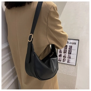Detail of minimalist black hobo bag with gold buckle and wide shoulder strap