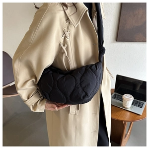 Close-up of black quilted cloud bag featuring heart patterns and knotted shoulder strap