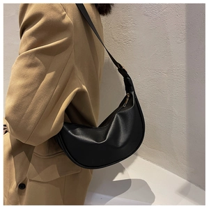 Detail of black crescent shoulder bag in vegan leather with golden zipper on a model