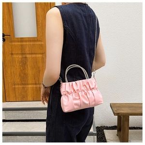 Detail of light pink pleated cloud bag with silver rhinestone handle on casual denim outfit