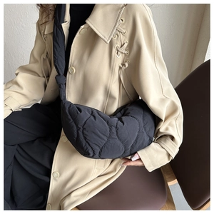 Detail of black quilted shoulder bag featuring soft texture and knot strap design