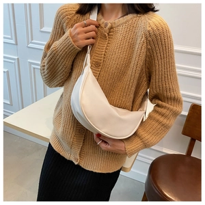 Model wearing a creamy white crescent crossbody bag with minimalist leather design