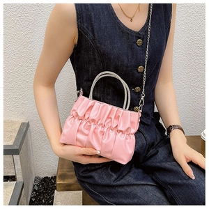 Detailed shot of pink pleated bag featuring luxury silver rhinestone handles and chain