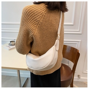 Detail view of the adjustable golden buckle on a white leather half-moon crossbody bag