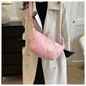 Detail of pink quilted shoulder bag with puffy knot strap shown on a model